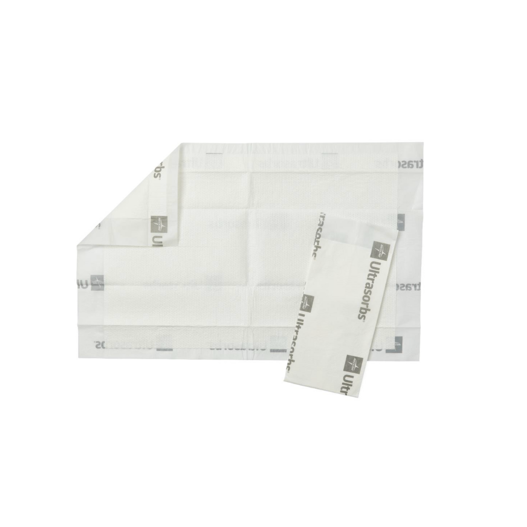 A rectangular, white Medline Ultrasorbs Premium Underpad - Superabsorbent is shown flat with one corner folded, and a smaller air-permeable dressing partly overlaps it. Both are displayed on a white background.