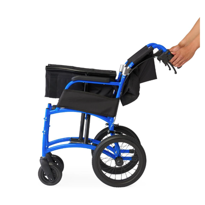 A hand folds the Medline Zero G Ultralite Transport Chair, a blue, lightweight aluminum model with black seat and accessories, featuring a foldable design, shown from the side against a white background.