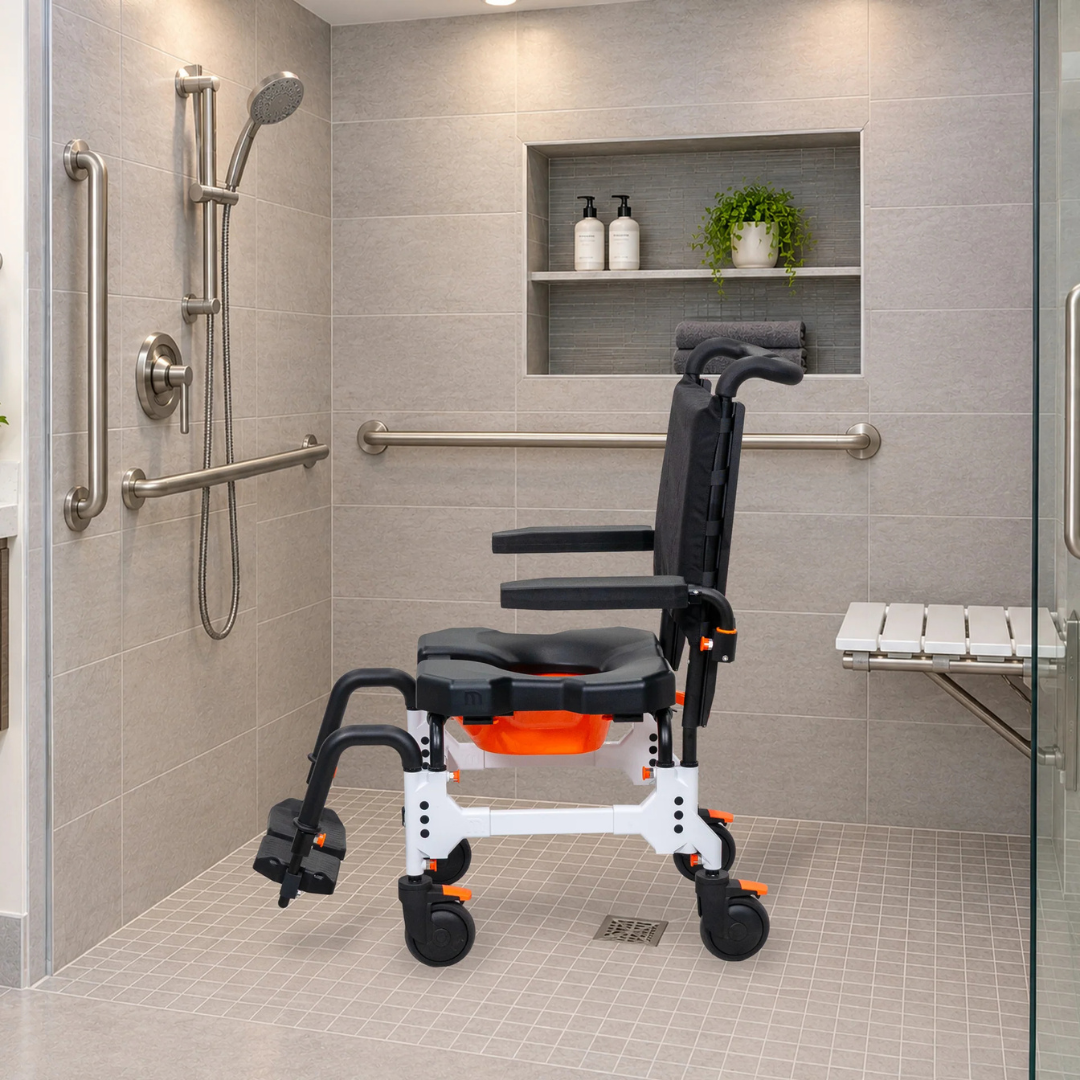 A MetaPal® M1-AP Attendant-Propelled Shower Commode Chair with black armrests, seat, and backrest, positioned in a tiled accessible shower with grab bars and a fold-down bench.