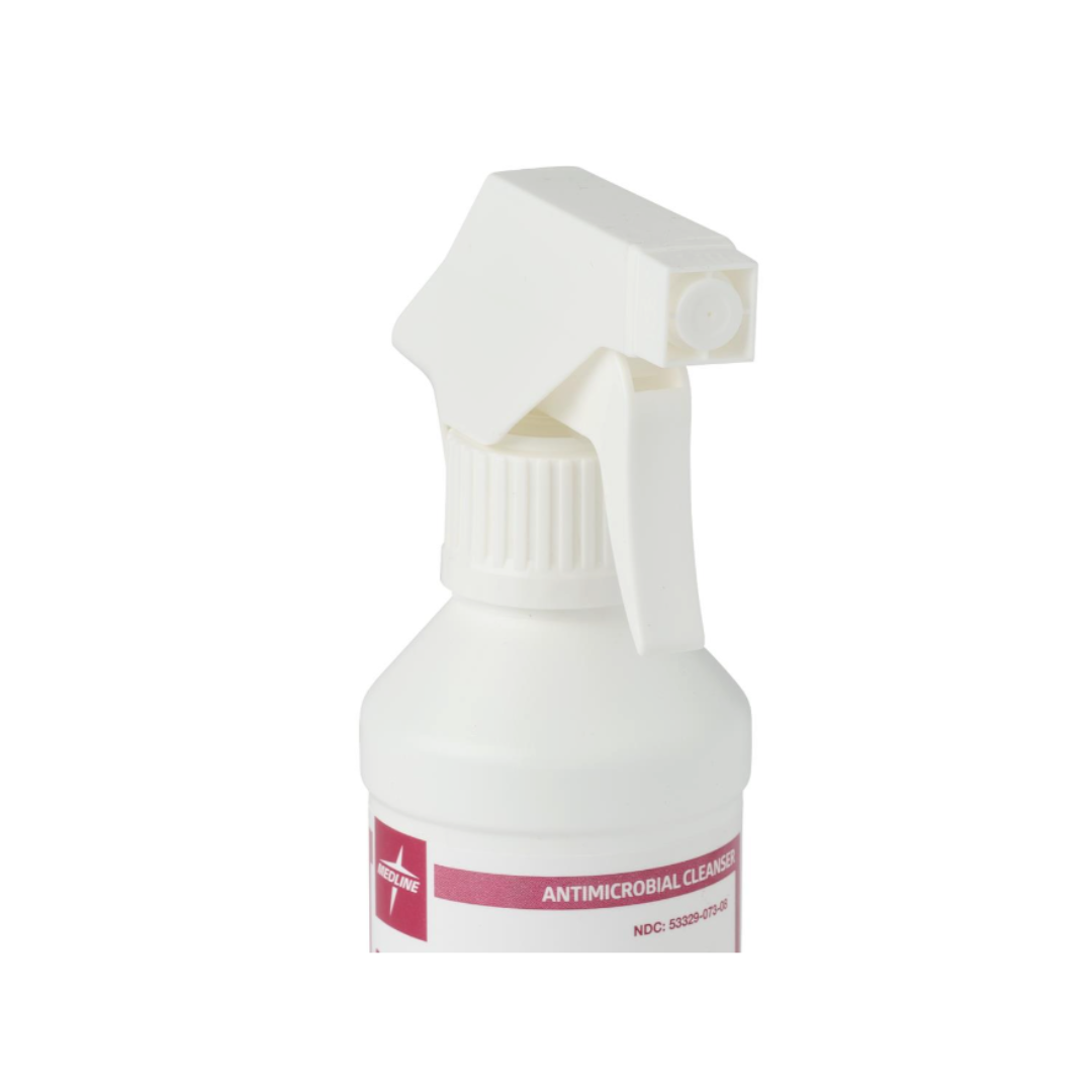 A white spray bottle with a trigger nozzle, partially visible, labeled Medline MicroKlenz Antimicrobial First Aid Antiseptic on a pink and white label. The background is plain white.