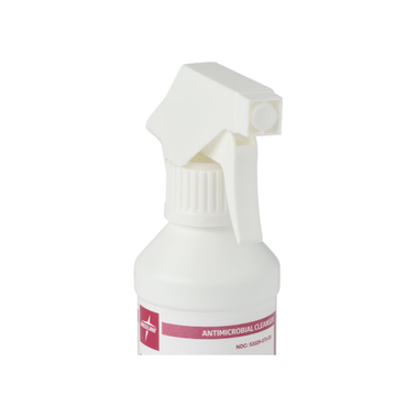 A white spray bottle with a trigger nozzle, partially visible, labeled Medline MicroKlenz Antimicrobial First Aid Antiseptic on a pink and white label. The background is plain white.