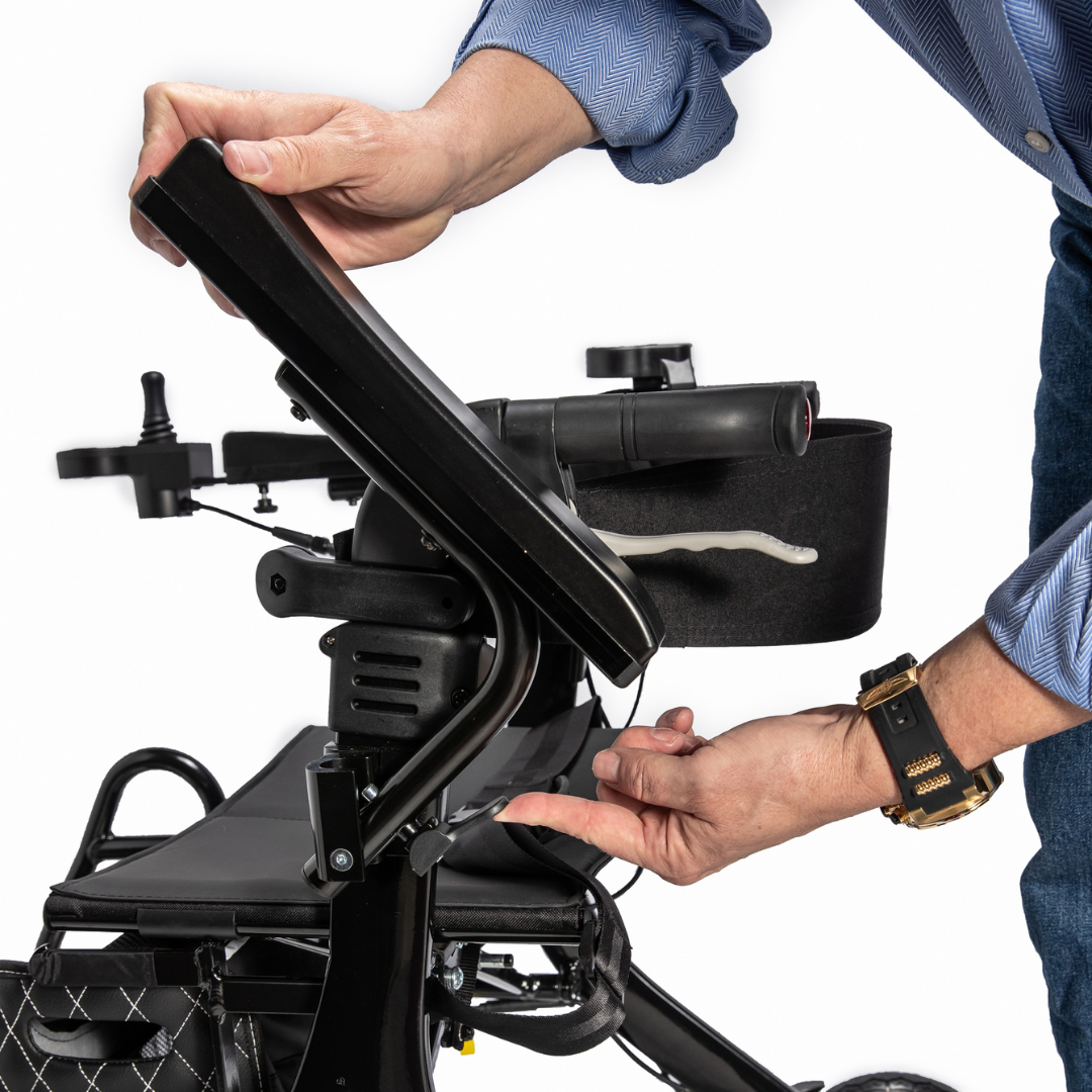 A person in a blue shirt and black wristwatch adjusts the joystick control panel of the Miracle Mobility Portable 4N1 Walker Wheelchair Combo, using one hand to turn a knob and the other to lift the panel.