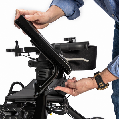 A person in a blue shirt and black wristwatch adjusts the joystick control panel of the Miracle Mobility Portable 4N1 Walker Wheelchair Combo, using one hand to turn a knob and the other to lift the panel.