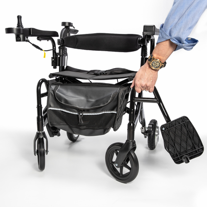 A person’s hand holds the Miracle Mobility Portable 4N1 Walker Wheelchair Combo, a lightweight travel-ready mobility aid with a black storage bag attached to the front, displayed against a white background.