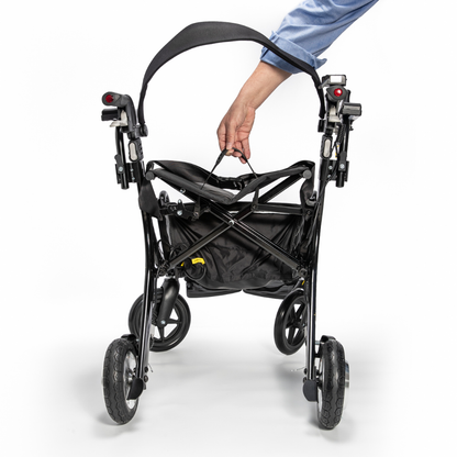 A hand pulls the Miracle Mobility Portable 4N1 Walker Wheelchair Combo by its strap while folded, highlighting its large wheels, storage basket, and compact, travel-friendly design against a white background.