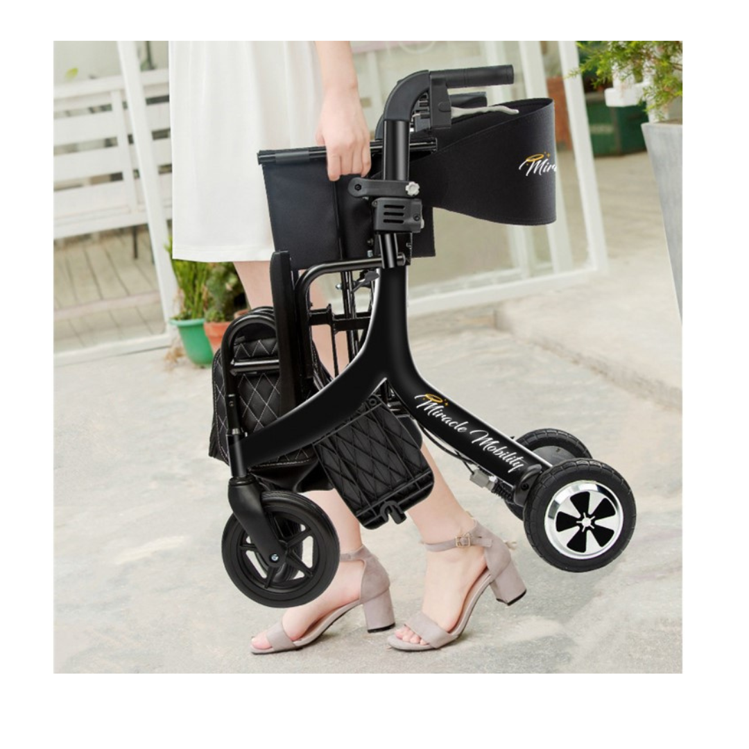 A woman in a white dress and heeled sandals carries the Miracle Mobility Portable 4N1 Walker Wheelchair Combo with a side bag, standing outdoors on a concrete path near a building.