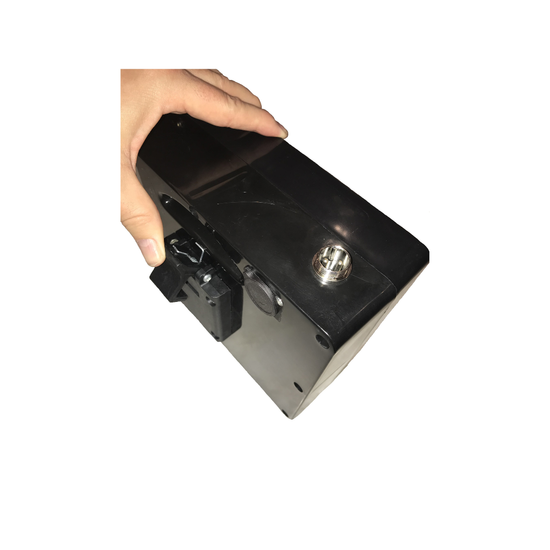 A hand holds a black Battery for The Miracle Mobility 6000 & 8000 Powerchairs, showing its keyhole and latch mechanism against a white background.