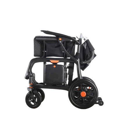 The Foldawheel Model CX Lightweight Portable Powerchair—just 28 lbs—is shown in black and orange, folded compactly for easy storage or transport, reminiscent of an ultra-lightweight stroller, set against a white background.