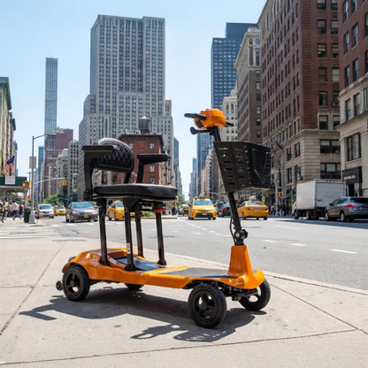A Monarch Genie Ultralight Portable Mobility Scooter with a black seat and basket is parked on a city sidewalk among tall buildings and yellow taxis, offering accessible urban transportation.