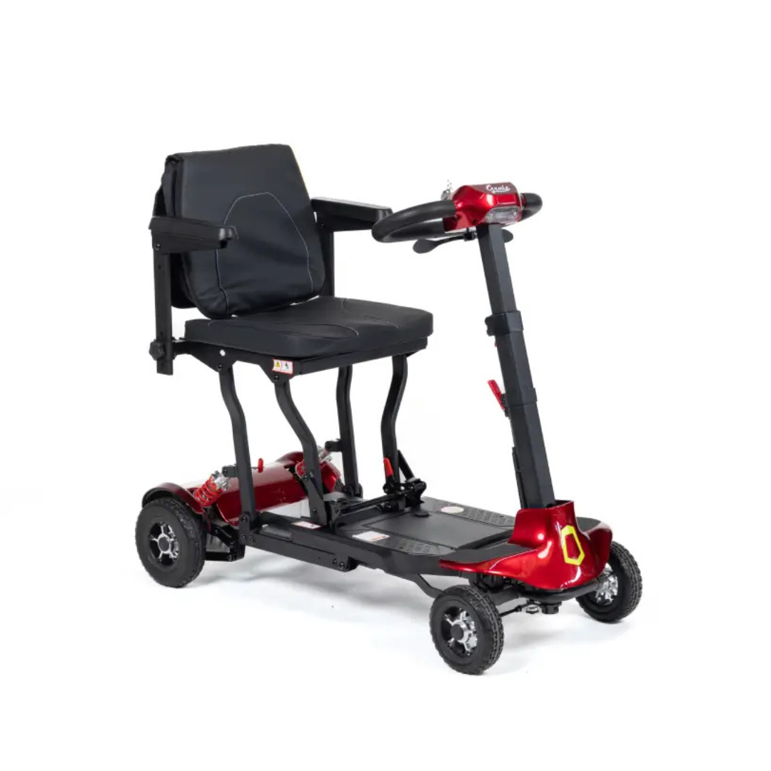 The Monarch Genie Lightweight Portable Scooter is a compact, four-wheeled scooter with a red frame, black seat, armrests, and backrest. It’s designed for personal transport and features a digital display with handlebars for easy control.