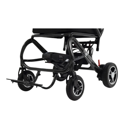 Close-up of the lower part of the Monarch MM60 Carbon Ultralite Electric Wheelchair, highlighting its wheels, footrest, and battery against a white background.