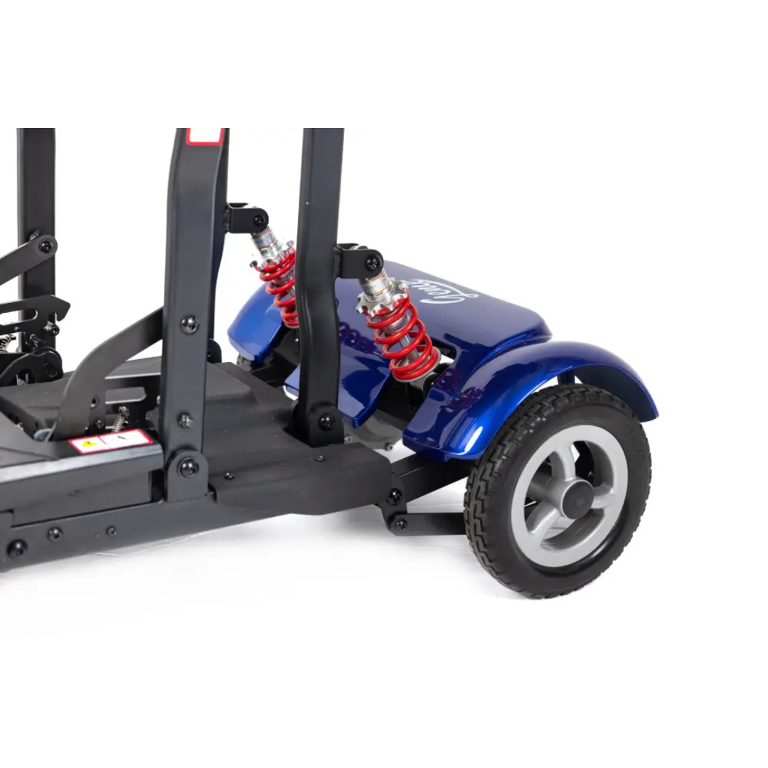 Close-up of the rear wheel and suspension on the Monarch Genie Auto Folding Portable Scooter, showing red coil springs, a durable black frame, and part of the rear fender for extra protection.