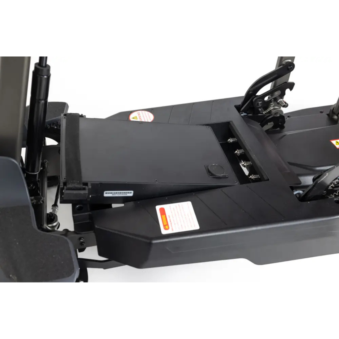 Close-up of the Monarch Genie Auto Folding Portable Scooter's black battery compartment, with the battery partially removed to show detailed labels and deck mechanisms for easier maintenance and enhanced safety.