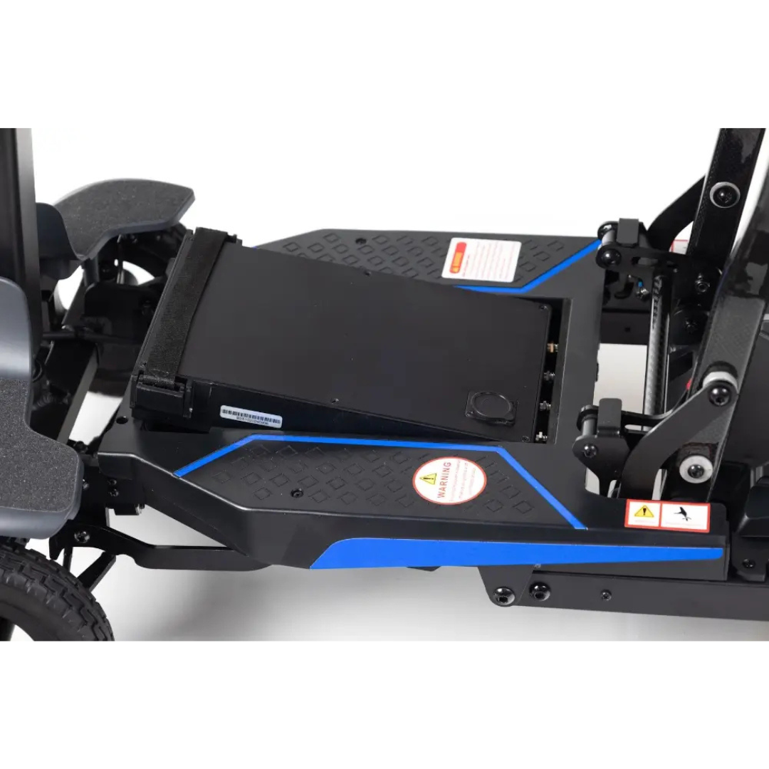 Close-up of the Monarch Supa Carbon Lite Ultra-Lightweight Carbon-Fiber Scooter’s base, featuring a black battery compartment with warning labels and blue platform accents for enhanced visibility and safety.