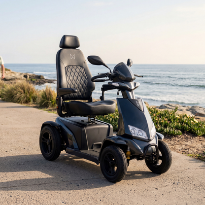 A Monarch Obsidian HD Outdoor Mobility Scooter with a high-back, cushioned seat is parked by the ocean. Watch videos and check specs to discover features and warranty details for added peace of mind.
