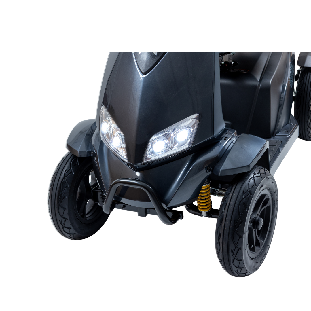 Close-up of the Monarch Obsidian HD Outdoor Mobility Scooter’s front, featuring two headlights on, front wheels, and yellow suspension springs against a white background—see specifications for more details.