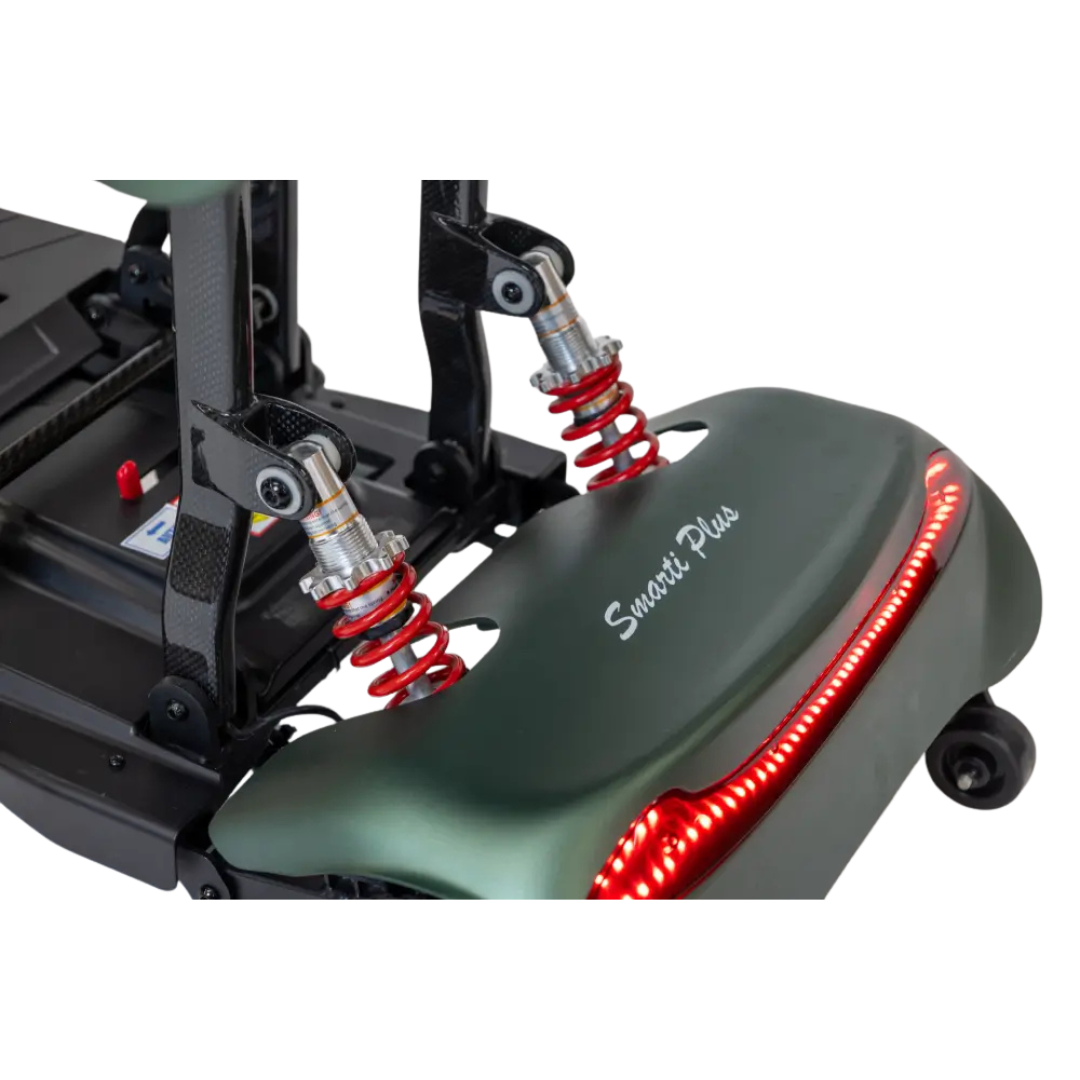 Close-up of the Monarch Smarti Plus Ultra-Lite Auto Folding Scooter’s rear suspension system, with red coil springs, LED tail light, and Smarti Plus branding on a green panel.