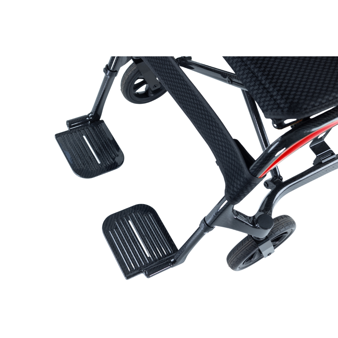 Close-up of the footrests and lower frame of a black Monarch Ezi Fold Carbon Portable Power Wheelchair, showing the textured foot supports and compact front wheels.