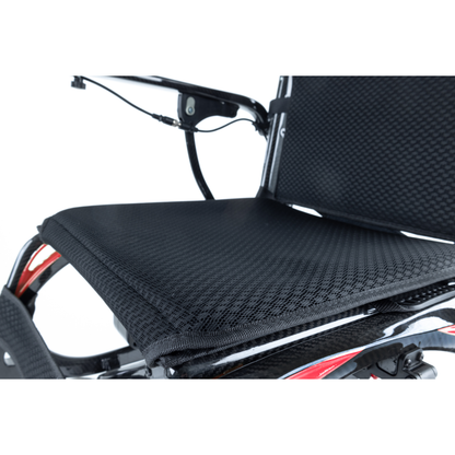Close-up of the black, textured seat and backrest on the Monarch Ezi Fold Carbon Portable Power Wheelchair, showcasing its mesh fabric, support structure, and a section of the durable frame and armrest.