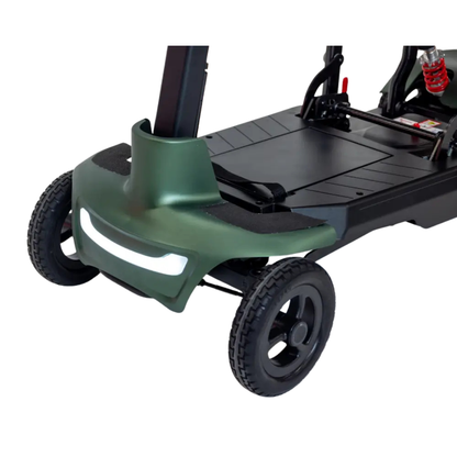 Close-up view of the Monarch Smarti Plus Ultra-Lite Auto Folding Scooter's front, featuring two wheels, green bumper, white headlight, and part of the black footrest with visible metal and suspension components.