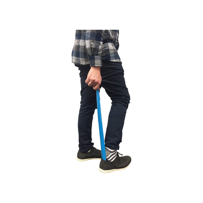 A person uses the Nova 24″ Extra Long Shoe Horn from the Pack of 2 to comfortably slip on black shoes. Wearing dark pants, a plaid shirt, and striped socks, they find it effortless to put on their shoes thanks to the extra-long design of the blue shoe horn.
