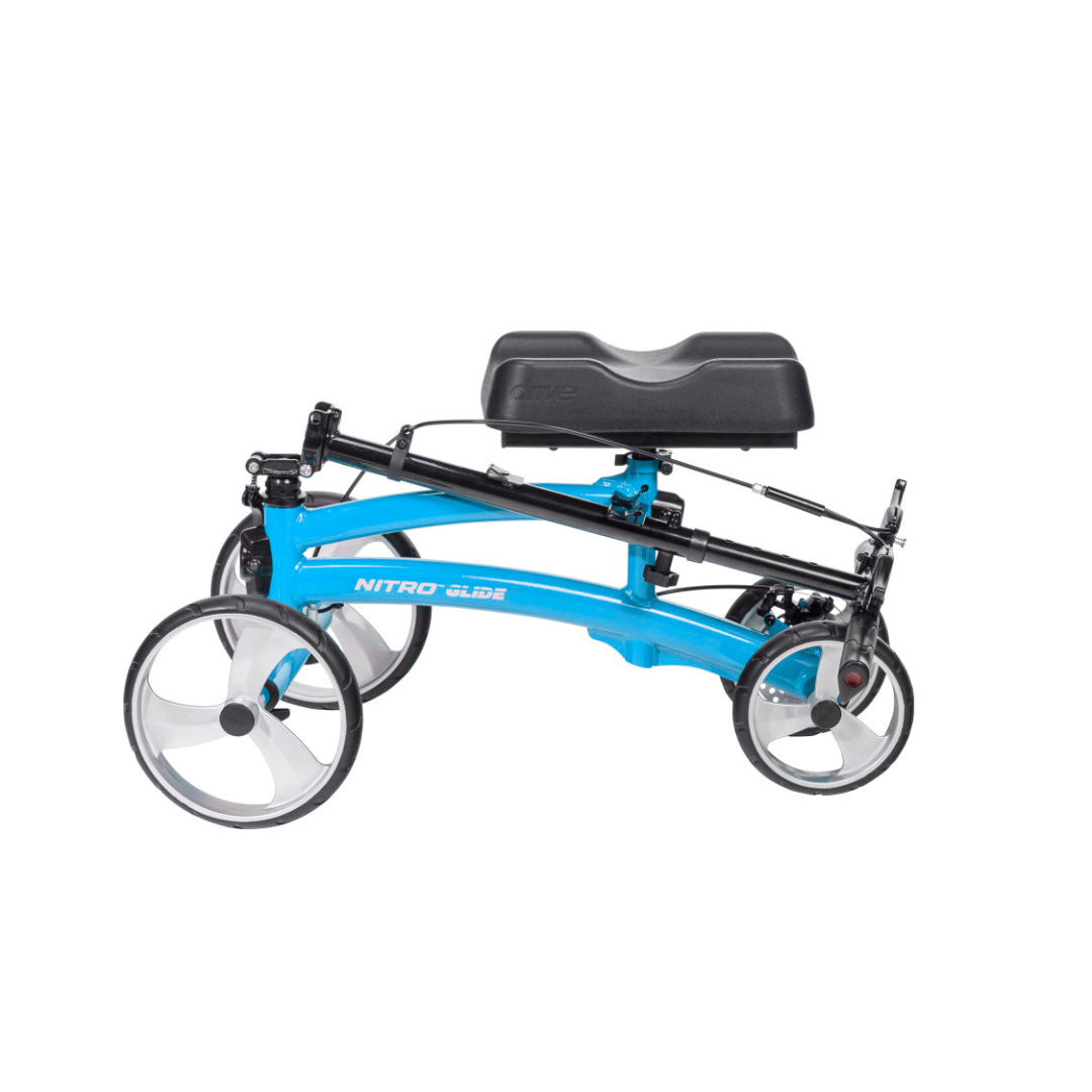 The Drive Folding Nitro® Glide Knee Walker features a blue frame, four large wheels, and a black cushioned knee rest. Lightweight and foldable, it offers a crutches alternative for mobility on a white background.