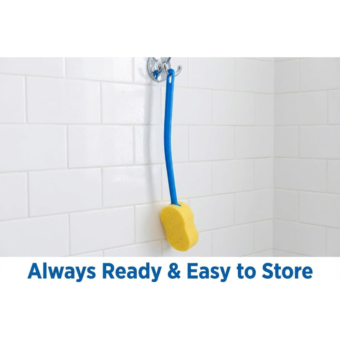 A Nova 23” Extra Long Bath & Back Sponge Brush (2 Pack) with a yellow sponge and blue handle hangs from a suction cup on a white tiled shower wall. Text below reads, Always Ready & Easy to Store.