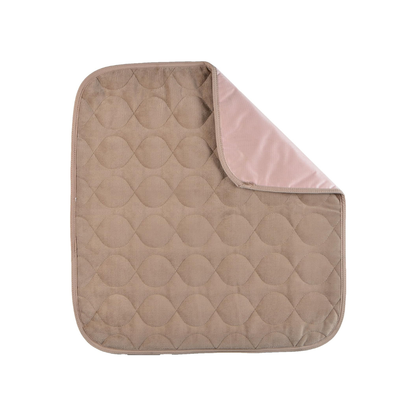 The Nova Ultra Reusable Waterproof Underpad For Chairs (21" x 22") is a quilted, square, beige pad with rounded corners and a light pink underside, shown partially folded on a white background.