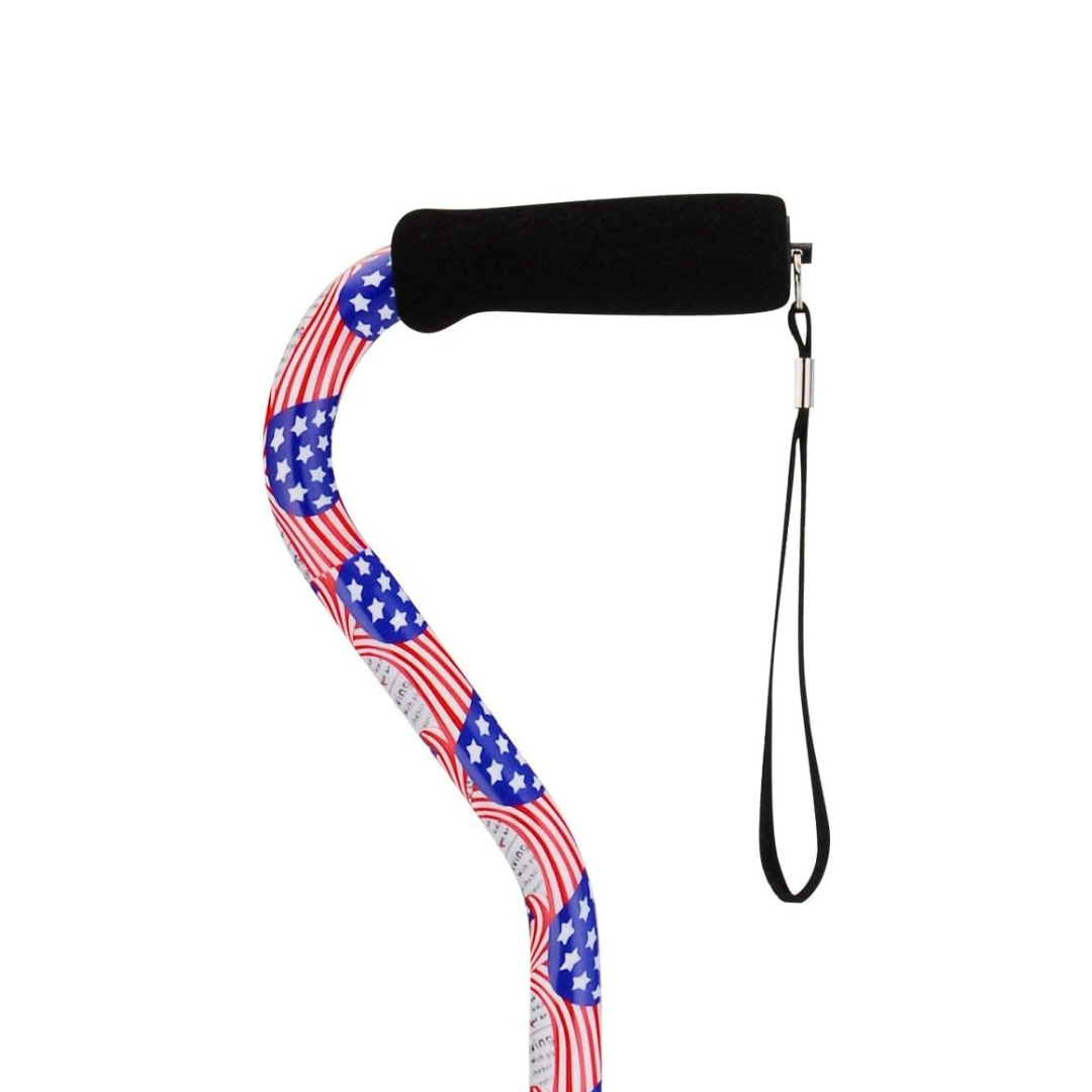 The Nova Designer Offset Walking Cane features a black foam handle, wrist strap, and a patriotic red, white, and blue American flag with stars pattern on the shaft.