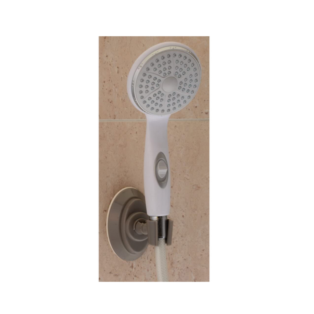 A white handheld showerhead with a circular spray face is mounted on a beige tiled wall, held securely in place by a silver Nova Suction Cup Showerhead Holder.