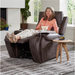 A woman relaxes in her Golden Tech PR448 Titan Recliner with Lift Assist & MaxiComfort® - Medium, feet up and smiling, wearing a peach shirt and beige pants. Beside her on a small table are a drink, book, and wireless phone charger. Through the large window, greenery is visible outside.