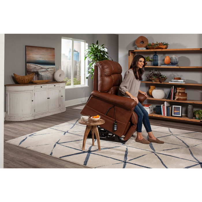 A woman relaxes on a Golden Tech PR515 Cloud Recliner With Lift Assist, ZG+ & Twilight in a modern living room featuring a geometric rug, wooden coffee table, and decorative bookshelf. A large window shows off the cityscape, while a side cabinet holds a basket.