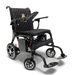 The ComfyGo Phoenix Carbon Fiber Electric Wheelchair features a quilted black seat, armrests, joystick control panel, foldable design with an emblem on the backrest, four wheels, and front-extended carbon fiber footrests.