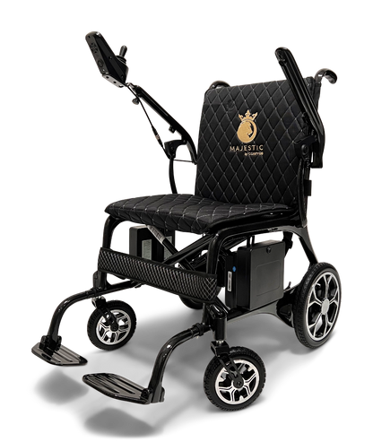 The ComfyGo Phoenix Carbon Fiber Electric Wheelchair offers a sleek, black design with a quilted seat cushion and foldable structure. It includes armrests, footrests, a control joystick, and features a backrest embroidered with Majestic in gold. Modern wheels sport metallic designs with carbon fiber accents.