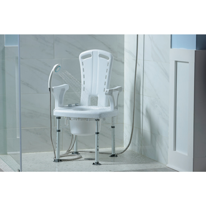 The Drive PreserveTech™ Aquachair Bathing System with Bidet, a white non-slip shower chair with armrests and adjustable legs, is placed in a tiled shower with water from a handheld showerhead spraying onto it and its removable bucket set beneath the seat.