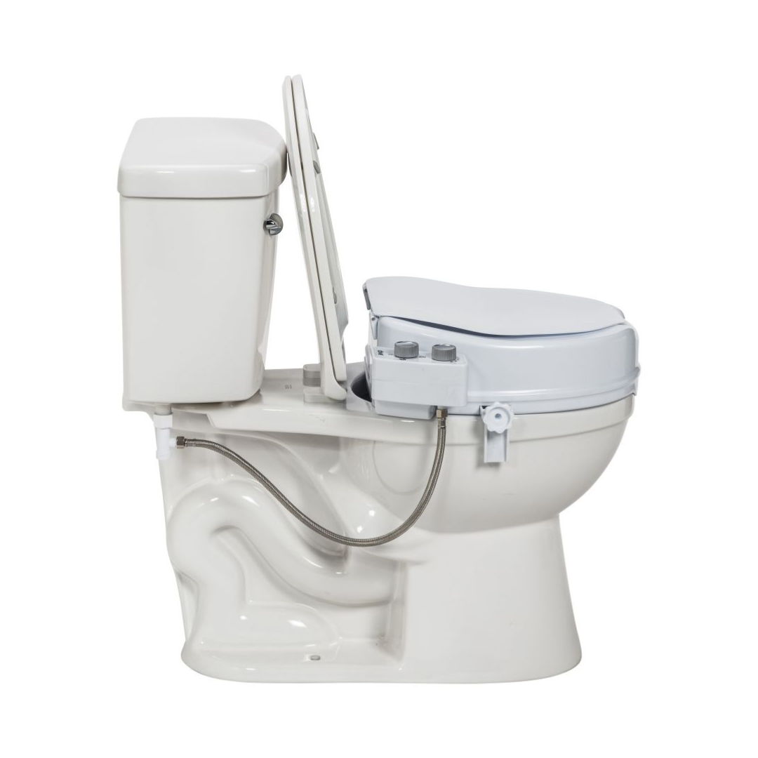 A side view of the Drive PreserveTech™ Raised Toilet Seat with Bidet - 4" Rise, in white, featuring control knobs and a hose connected to the plumbing.
