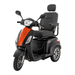 The Pride Baja® Raptor® 2 Bariatric 3-Wheel Scooter features a stylish orange and black body, padded seat with headrest and armrests, large LED headlight, rearview mirrors, and alloy wheels—perfect for outdoor mobility.