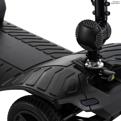 Close-up of a black Pride Go Go® Ultra X Gen 3 Portable Mobility Scooter’s textured footrest and front wheel area, showcasing detailed tread patterns and a section of the steering column. This portable scooter exemplifies both functionality and carefully considered design in every detail.