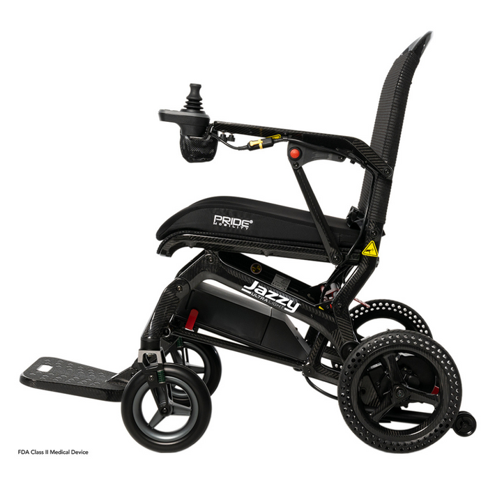 Side view of a black Pride Mobility Jazzy® Ultra Light Portable Electric Wheelchair featuring a cushioned seat, armrests, right-arm joystick, foldable design with footrest. The compact build has an ultra-light frame for easy transport and storage.
