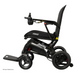 Side view of a black Pride Mobility Jazzy® Ultra Light Portable Electric Wheelchair featuring a cushioned seat, armrests, right-arm joystick, foldable design with footrest. The compact build has an ultra-light frame for easy transport and storage.