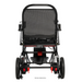 Rear view of the Jazzy® Ultra Light Portable Electric Wheelchair in black and red, showcasing its carbon fiber frame. The image highlights the backrest, handle, and large wheels, emphasizing its practical design with a sturdy yet lightweight construction.