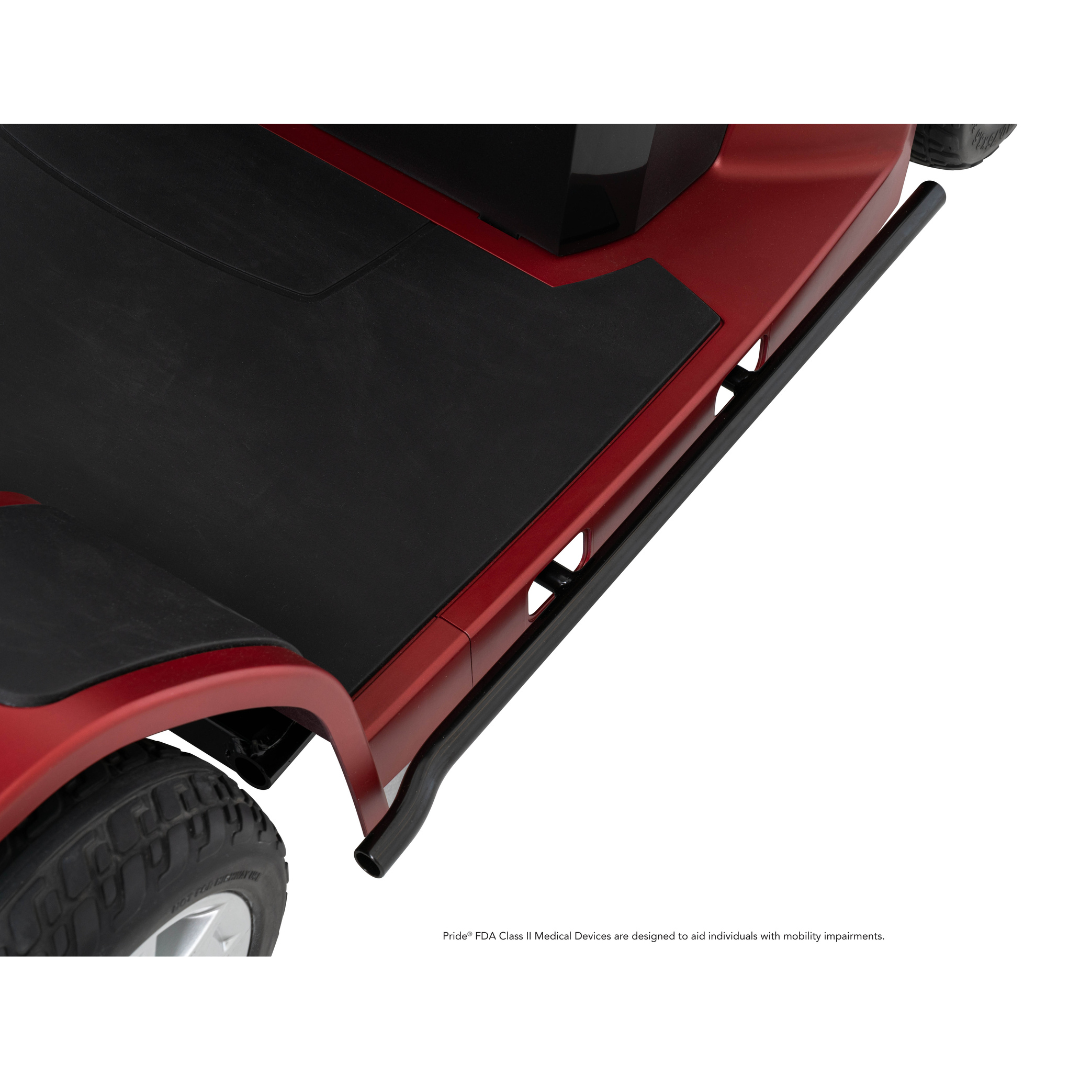 Close-up of the footrest and side rail on the red Pride Mobility Maxima 4-Wheel Bariatric Scooter, featuring part of the tire and black foot platform. Shown on a white background with a small disclaimer below.