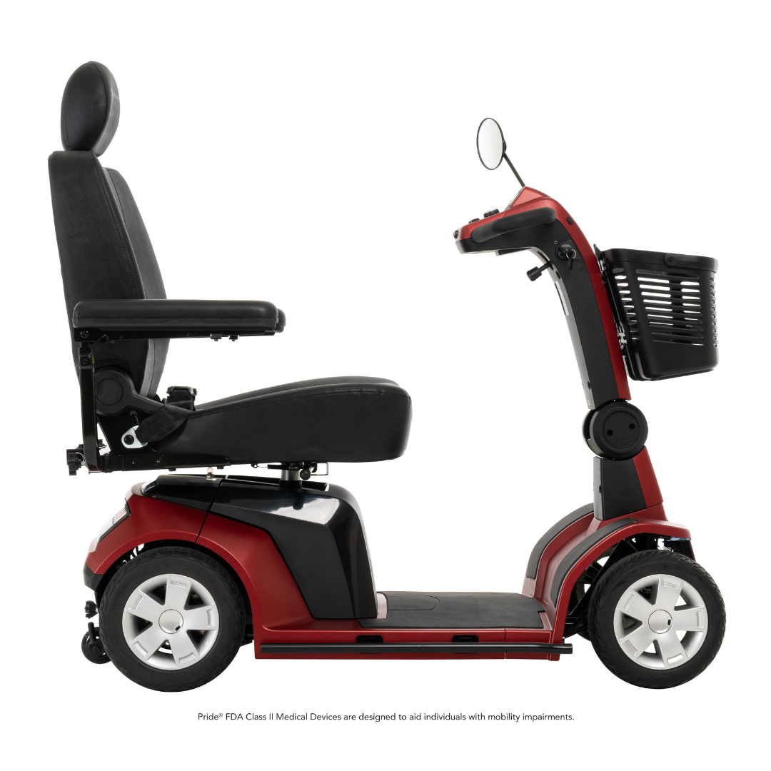 The Pride Mobility Maxima 4-Wheel Bariatric Scooter, in red and black, features a padded seat, armrests, basket, side mirror, and LED lighting package; side view shown against a white background.
