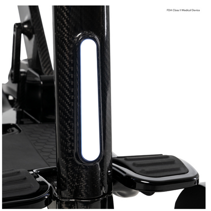 Close-up of the black carbon fiber seat post with step supports from the Pride Mobility GoGo Carbon Ultralite Mobility Scooter (35 lbs). A white rectangular light panel is embedded, and FDA Class II Medical Device text emphasizes its portable design.