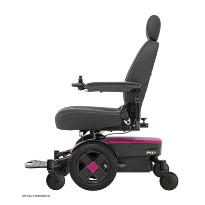 A side view of the black and pink Pride Mobility Jazzy® EVO 613 Powerchair with ATX Suspension, featuring a padded seat, backrest, armrests, footplate, joystick control on the armrest, and Mid-Wheel 6® Technology for better maneuverability.