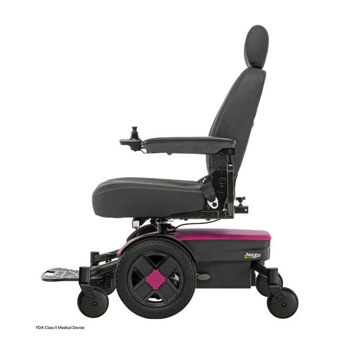 A side view of the black and pink Pride Mobility Jazzy® EVO 613 Powerchair with ATX Suspension, featuring a padded seat, backrest, armrests, footplate, joystick control on the armrest, and Mid-Wheel 6® Technology for better maneuverability.