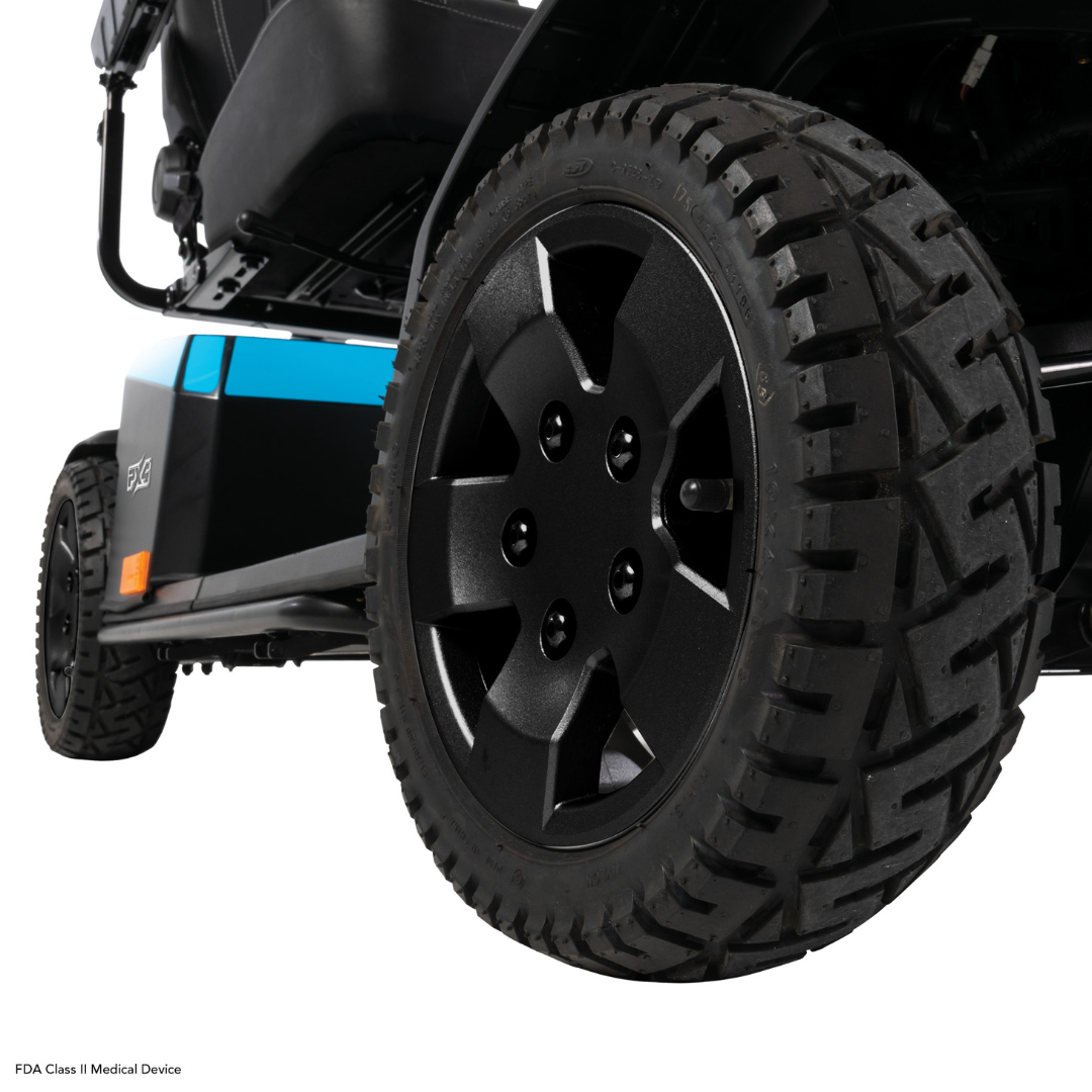 Close-up of the large, rugged rear wheel with textured tread and black rim on the Pride Mobility PX4 HD Bariatric Scooter, with part of the scooter body visible in the background.