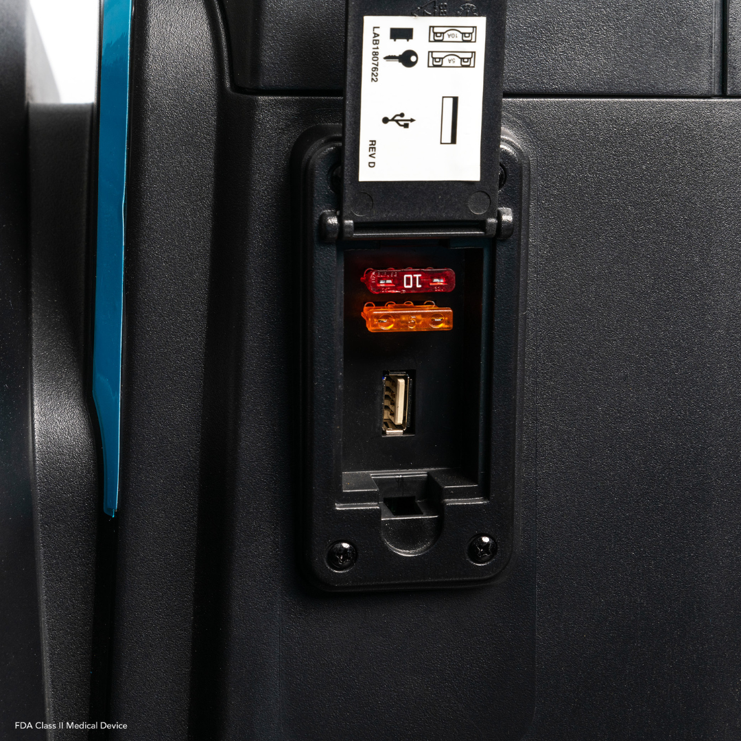 Close-up of the Pride Mobility PX4 HD Bariatric Scooter panel showing one red and one orange fuse above a USB port and an empty slot, with a reference guide attached above the panel.