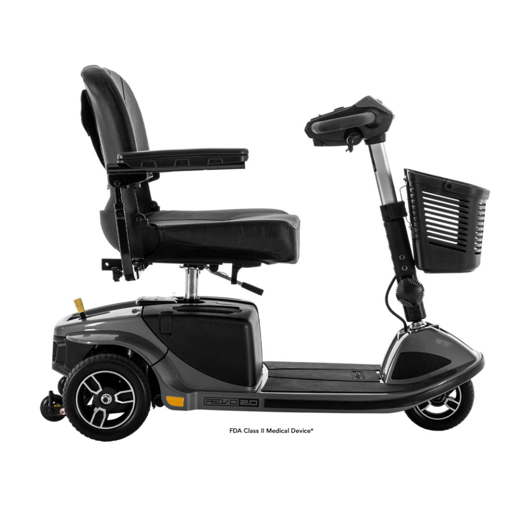 The Pride Mobility Revo® 2.0 3-Wheel Scooter, shown in black with comfort suspension, padded seat, armrests, front handlebar, and a front wire basket, is displayed side-on against a white background.
