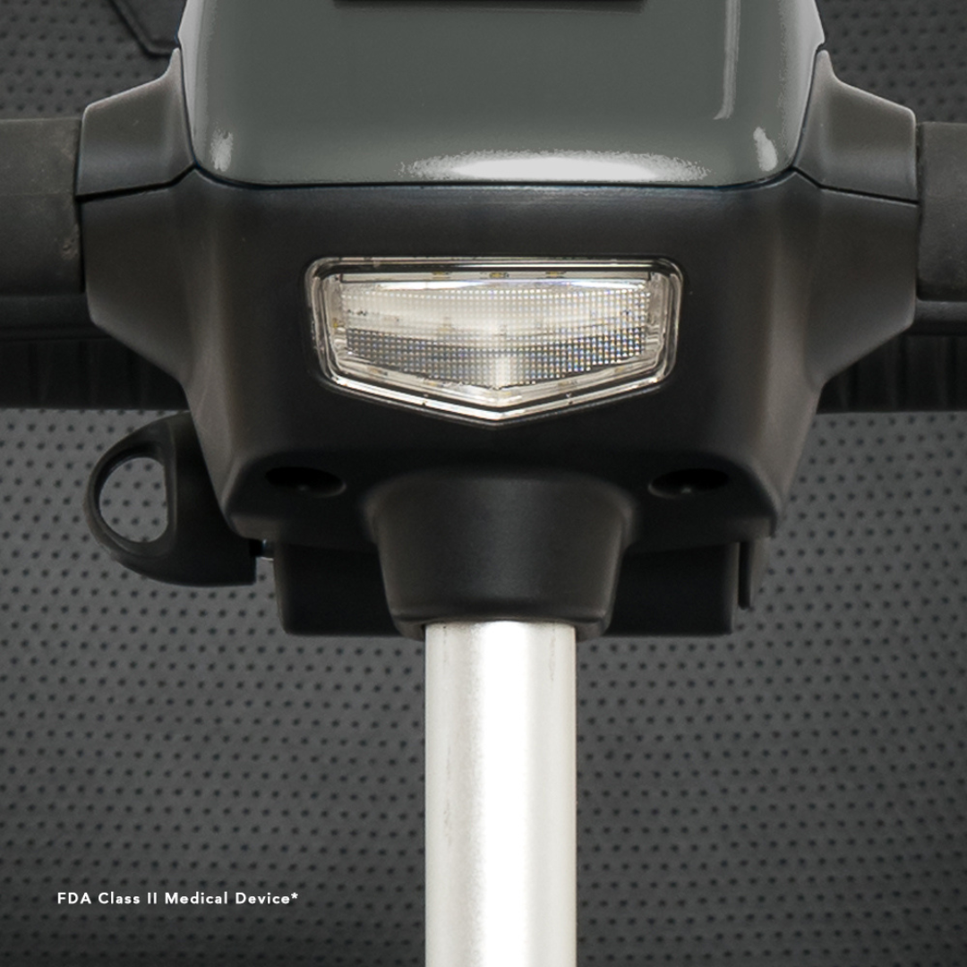 Close-up of the control panel and handlebar on the Pride Mobility Revo® 2.0 4-Wheel Scooter, featuring a gray and black design with metallic rod, small rectangular light, and text indicating FDA Class II Medical Device.